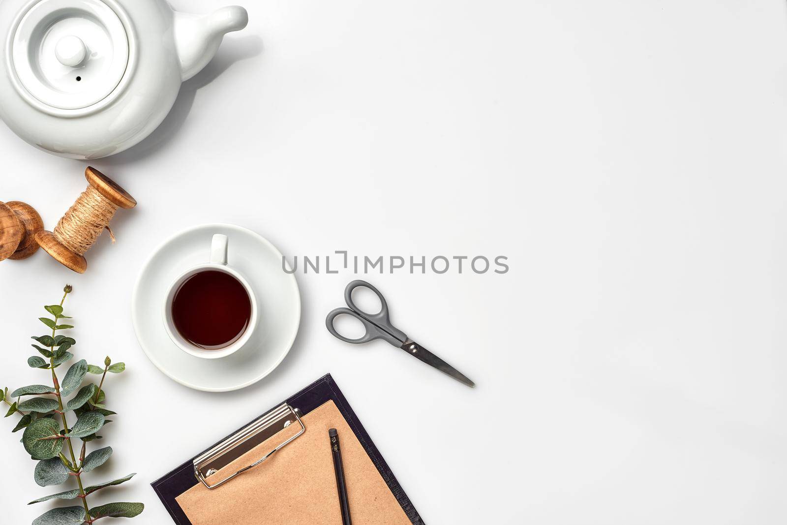 Still life with tea cup and the contents of a workspace composed. Different objects on white table. Flat lay. Top view. Copy space