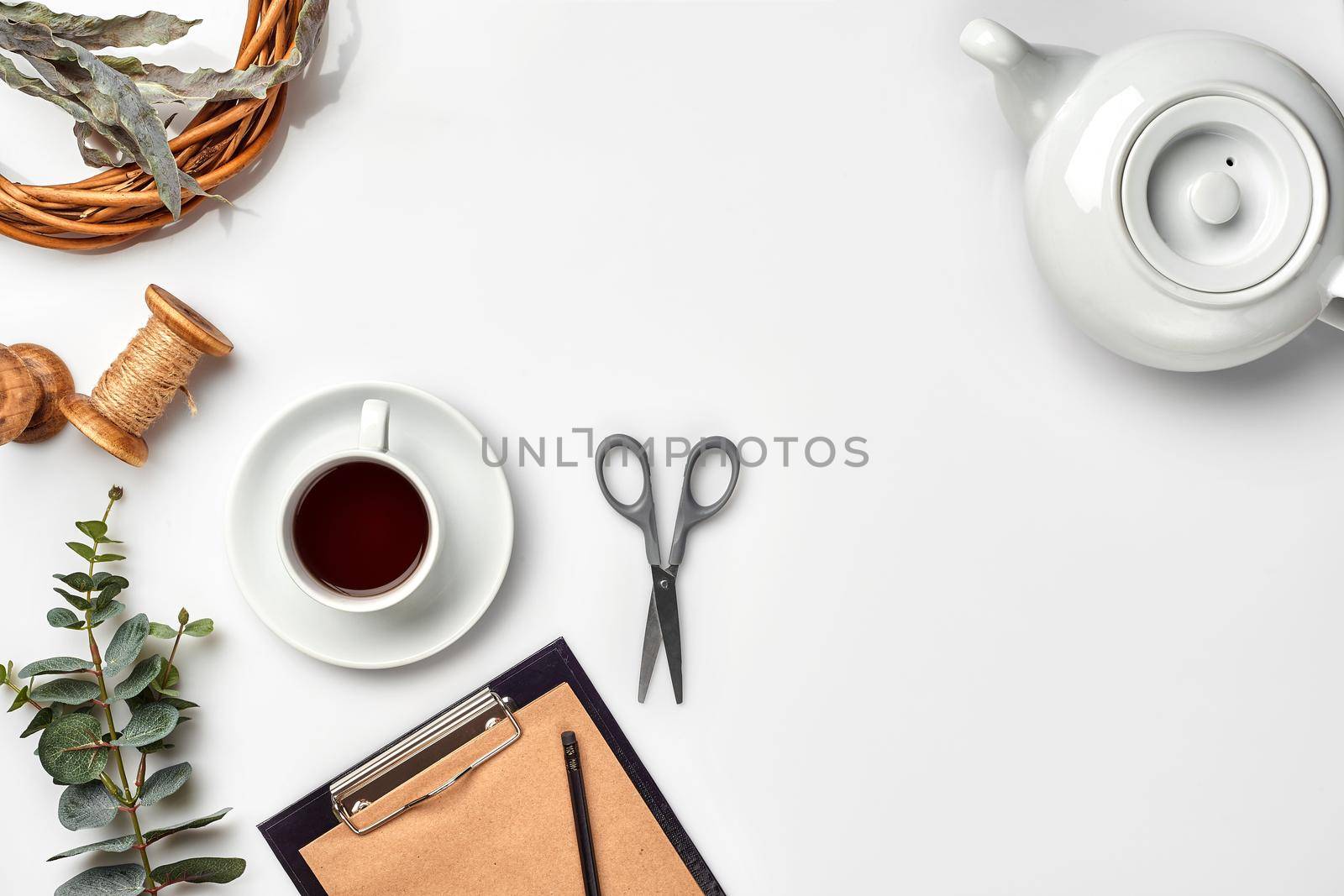 Still life with tea cup and the contents of a workspace composed. Different objects on white table. Flat lay by nazarovsergey