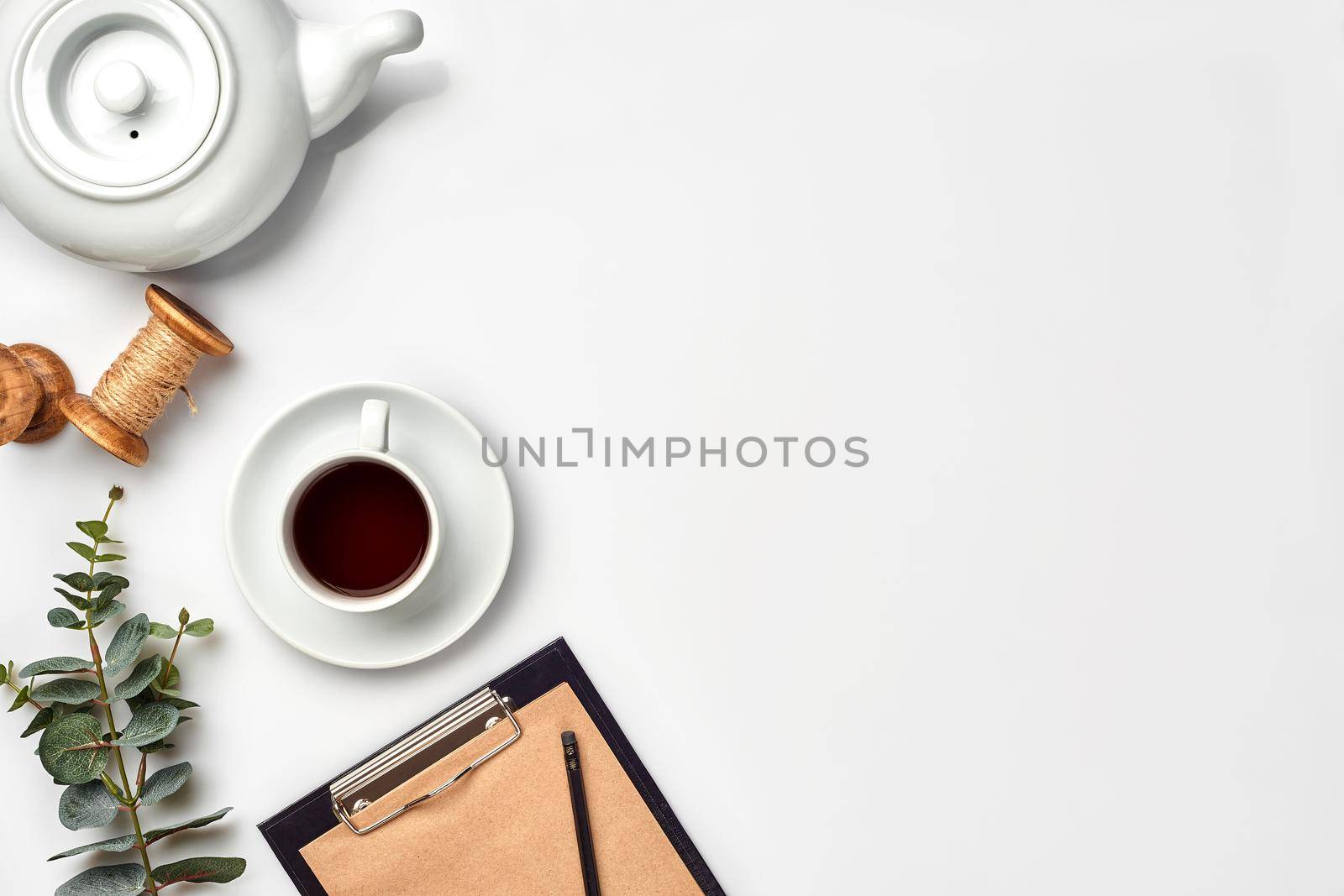 Still life with tea cup and the contents of a workspace composed. Different objects on white table. Flat lay. Top view. Copy space