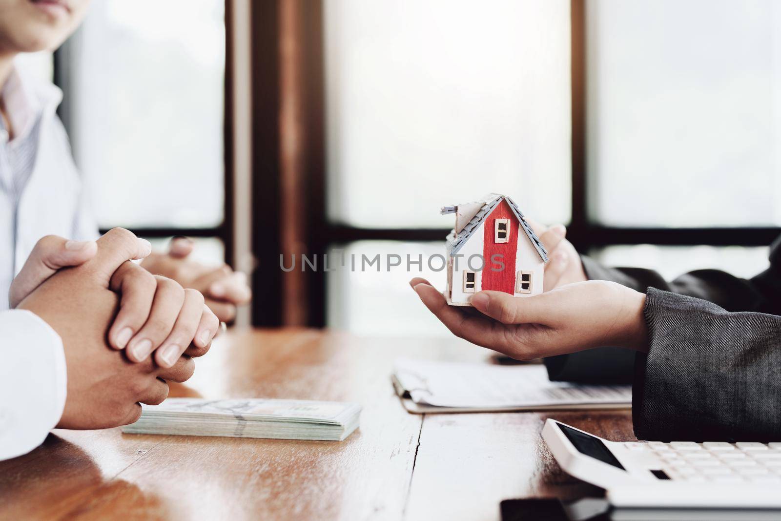 The real estate agent is showing the house model to the customer.