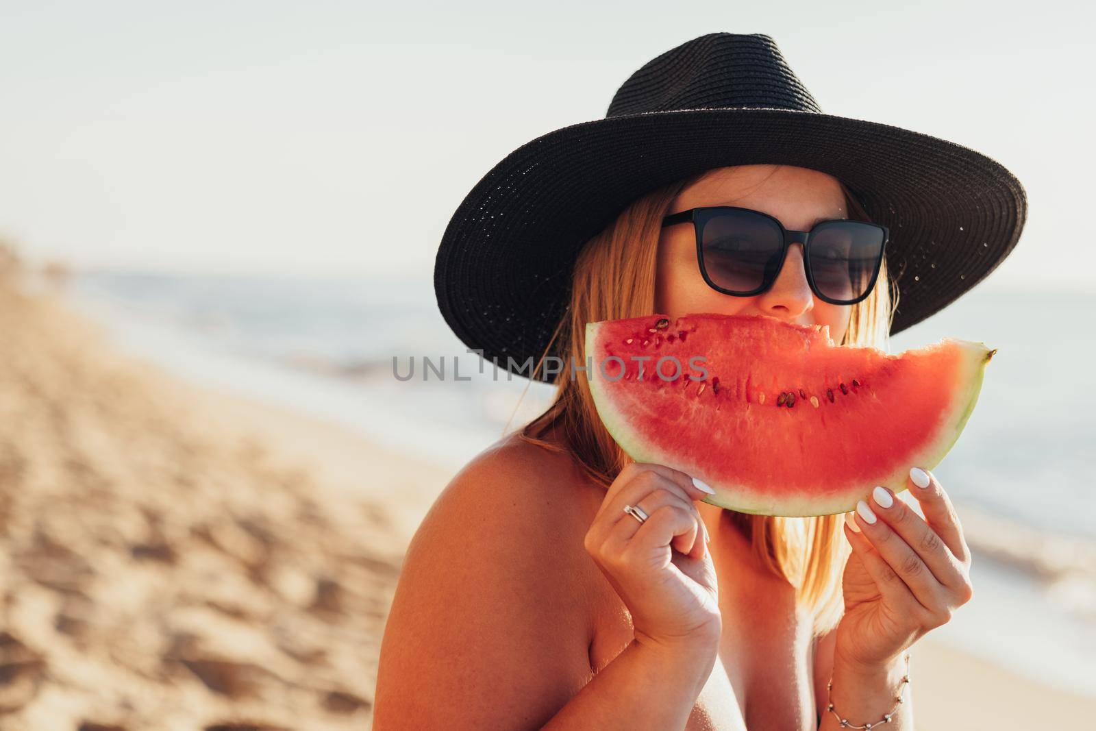 Portrait of Beautiful Young Woman in Hat and Sunglasses Cover Her Smile by Slice of Watermelon in Hands by Romvy