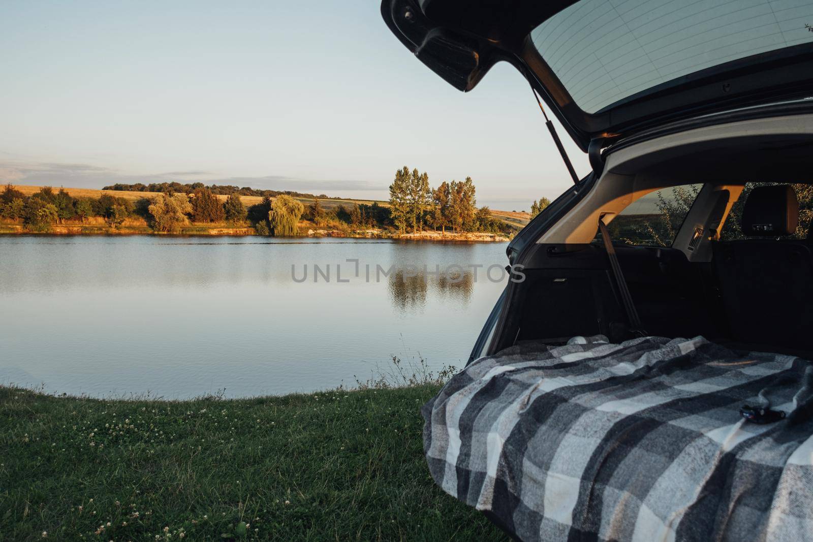 Opened Trunk of SUV Car on the Background of Country Lake, Road Trip Concept by Romvy