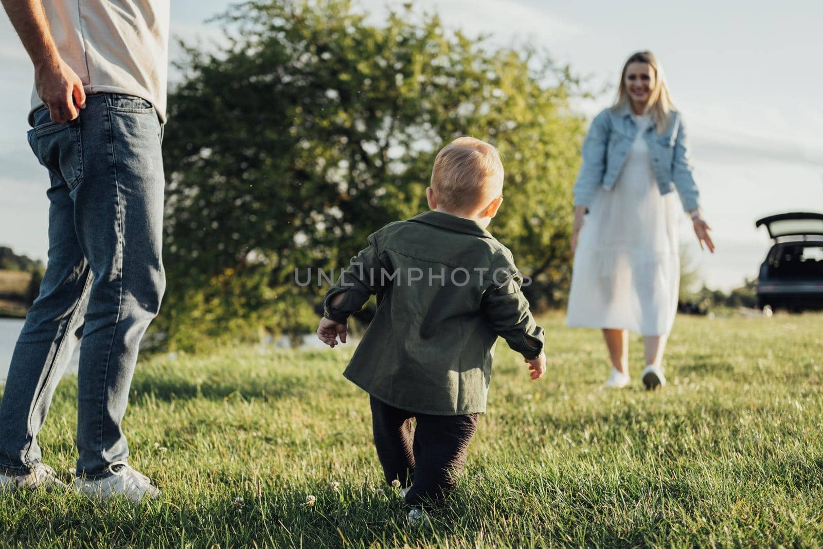 Happy Young Couple, Mom and Dad with Toddler Son Having Family Time Outdoors, Weekend Road Trip by Car by Romvy