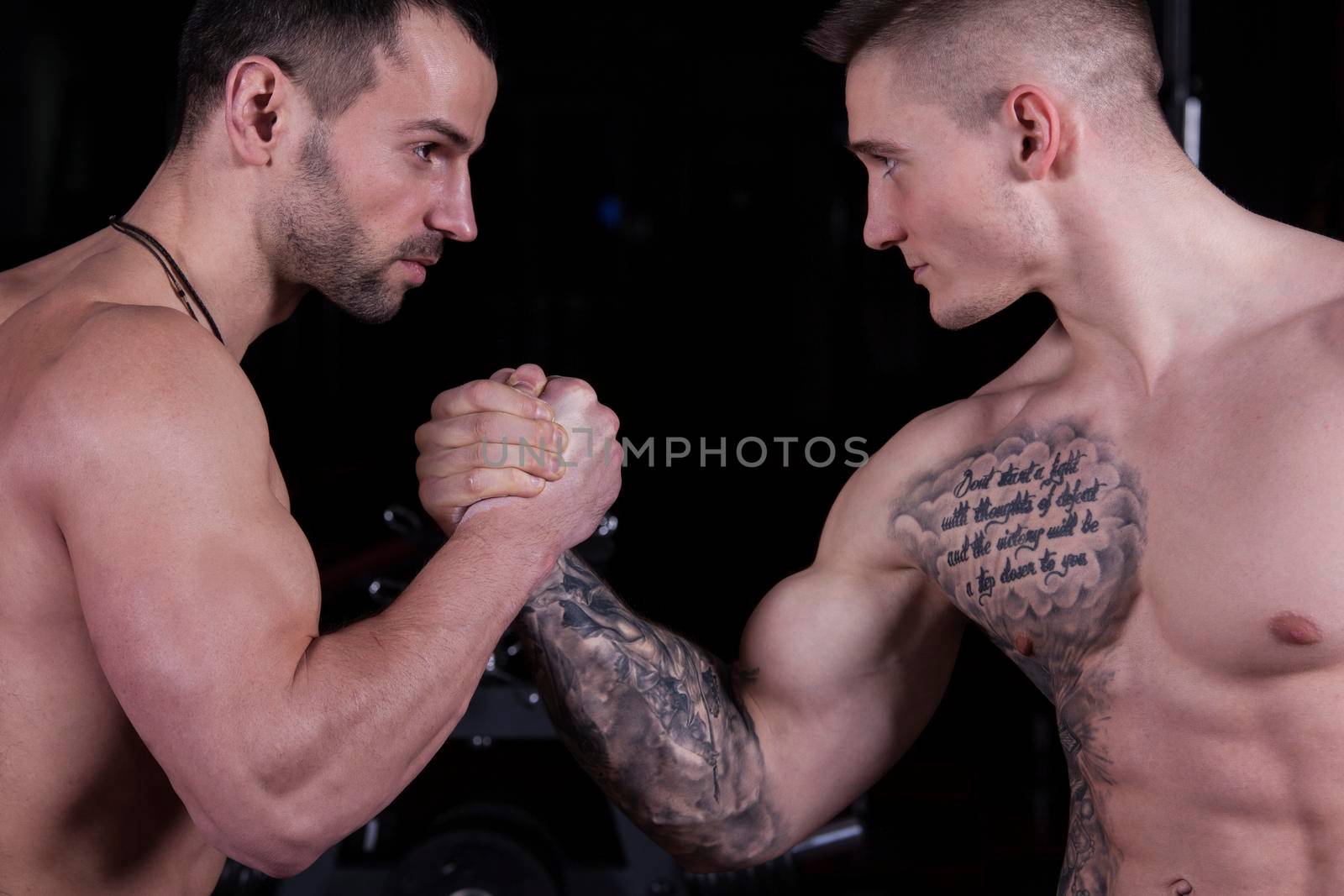 Arm wrestling. Two bodybuilders shake hands and look into each other's eyes