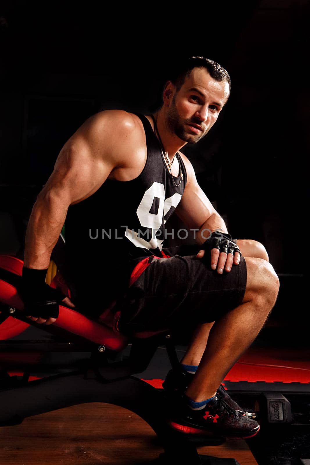 Close up portrait of a fit young man working out in sports simulators and looking at the camera on dark background