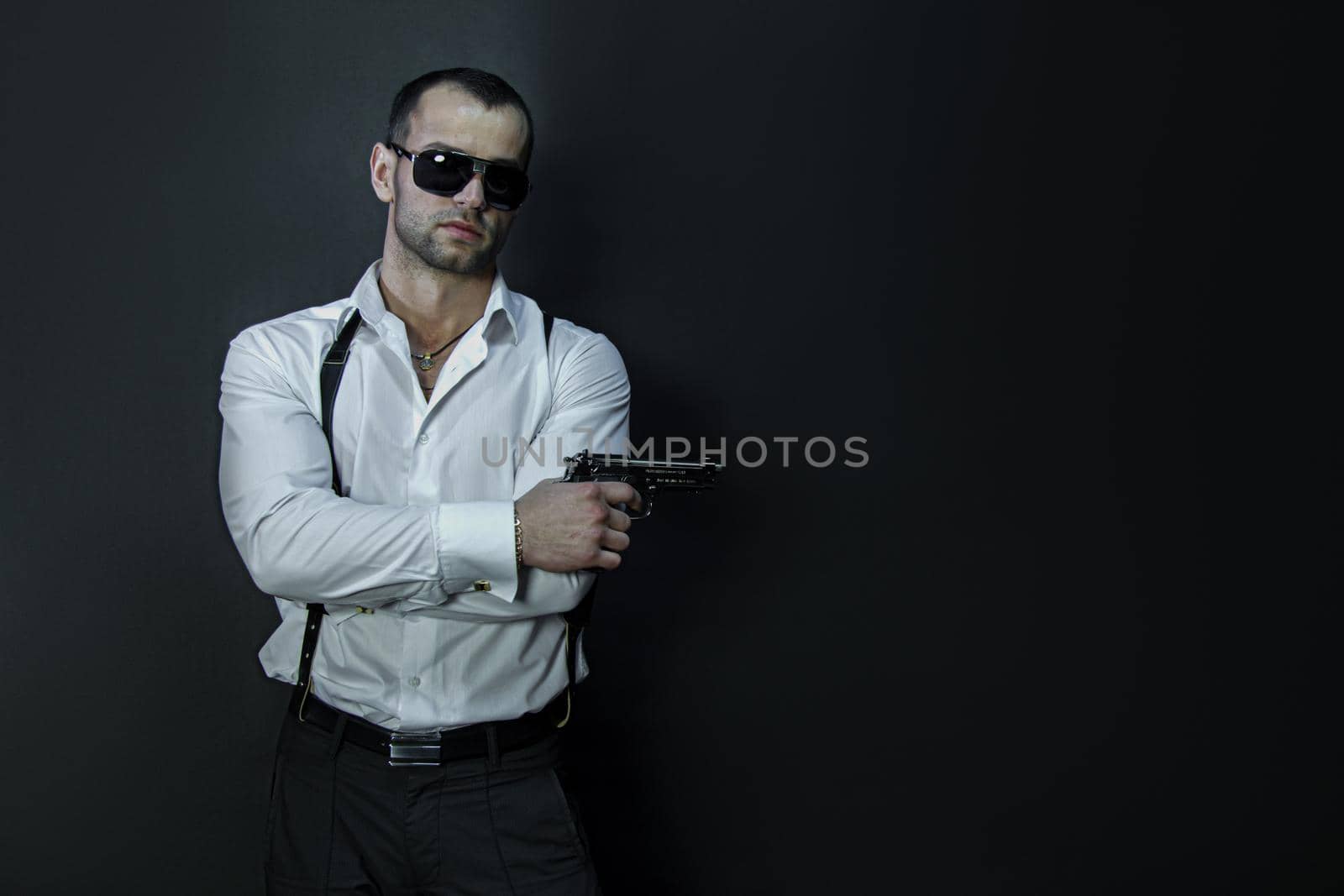 Young man in glasses wears holds a gun in his hand by studiodav