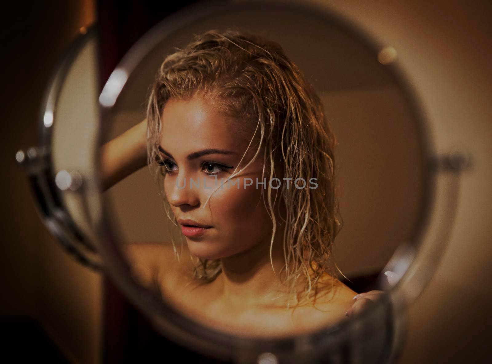 Sexy blonde girl with wet hair after bath loks in the mirror by studiodav