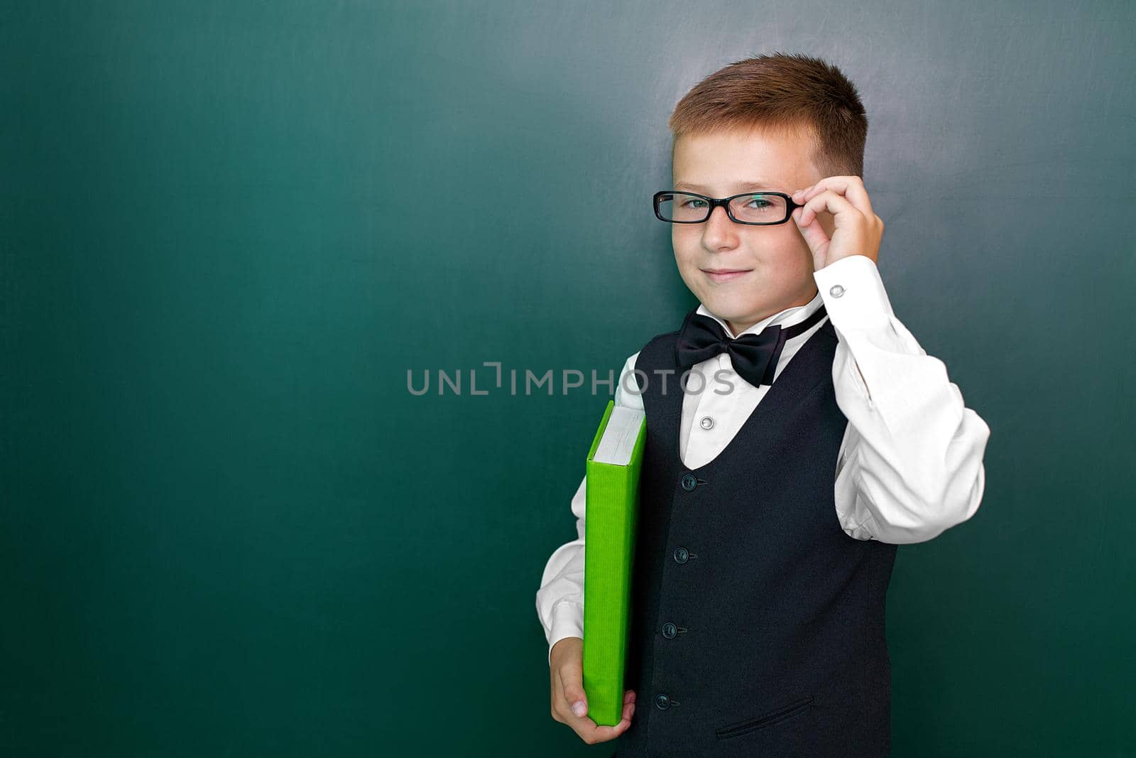 Happy cute clever boy with a bow tie and in glasses with book in his hand. First time to school. Back to school. by studiodav