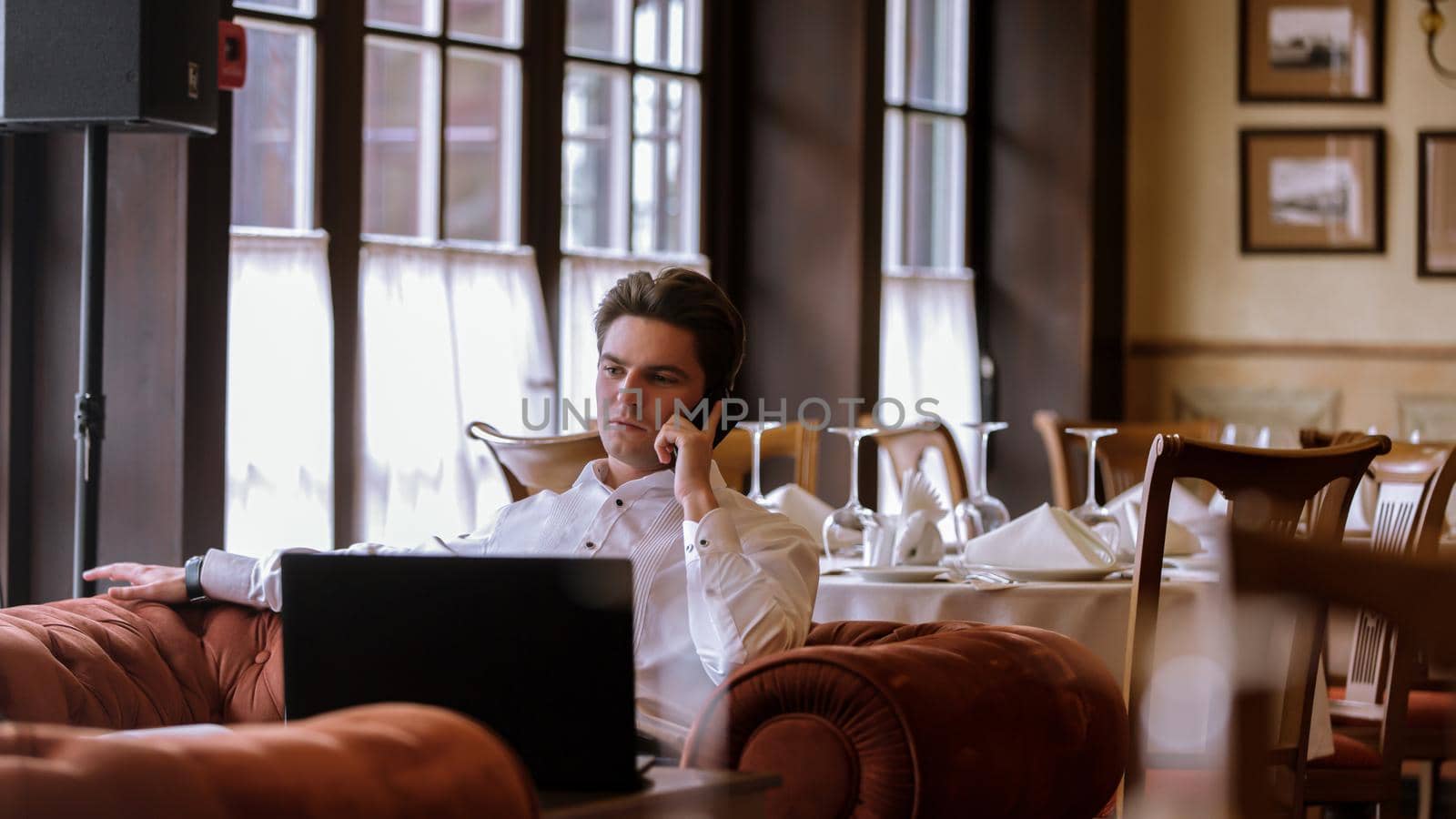 Portrait of goodlooking man sitting at table in restaraunt with laptop computer by studiodav