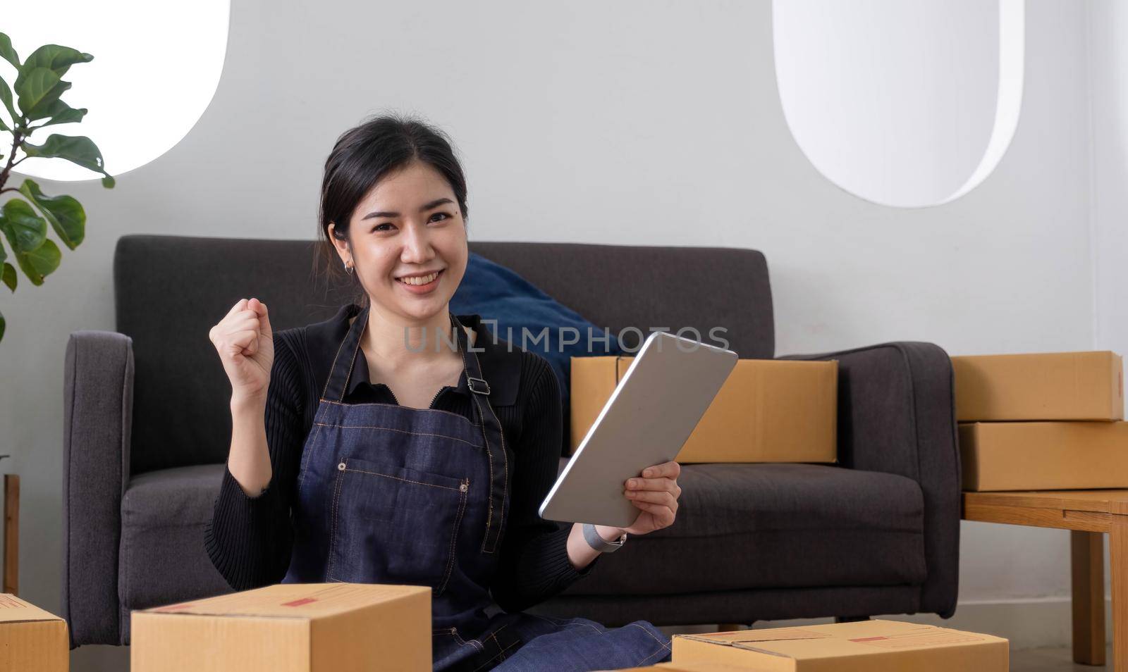 Startup SME small business entrepreneur of freelance Asian woman using a laptop with box Cheerful success Asian woman her hand lifts up online marketing packaging box and delivery SME idea concept by wichayada
