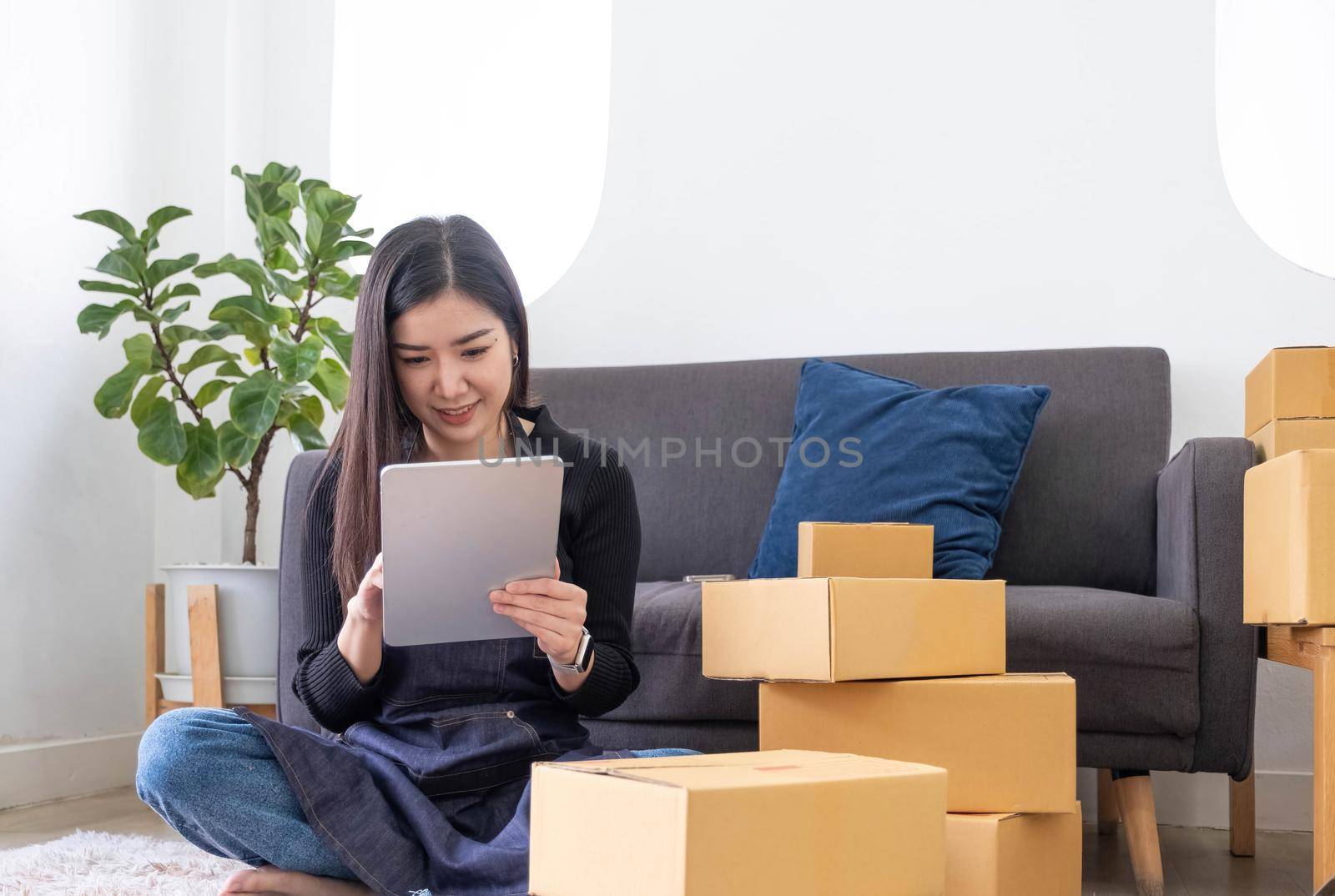 Portrait of Asian young woman SME working with a box at home the workplace.start-up small business owner, small business entrepreneur SME or freelance business online and delivery concept. by wichayada