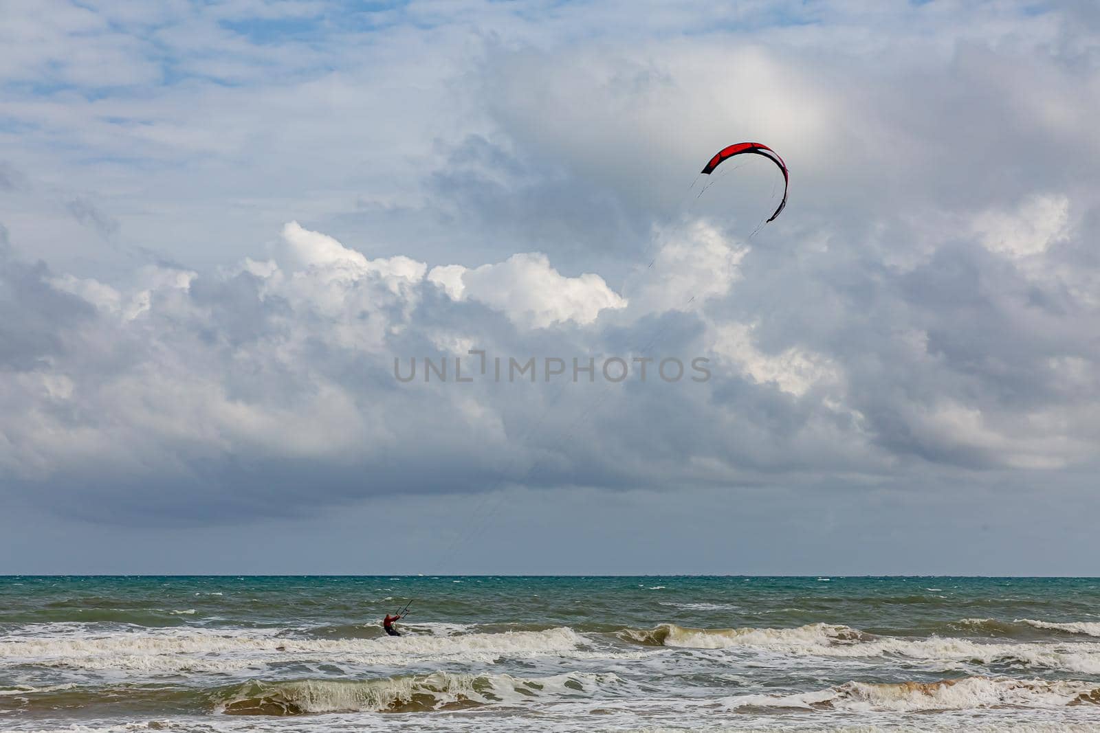 Professional kiter makes the difficult trick on a beautiful background. Kitesurfing Kiteboarding action photos man among waves quickly goes by Milanchikov