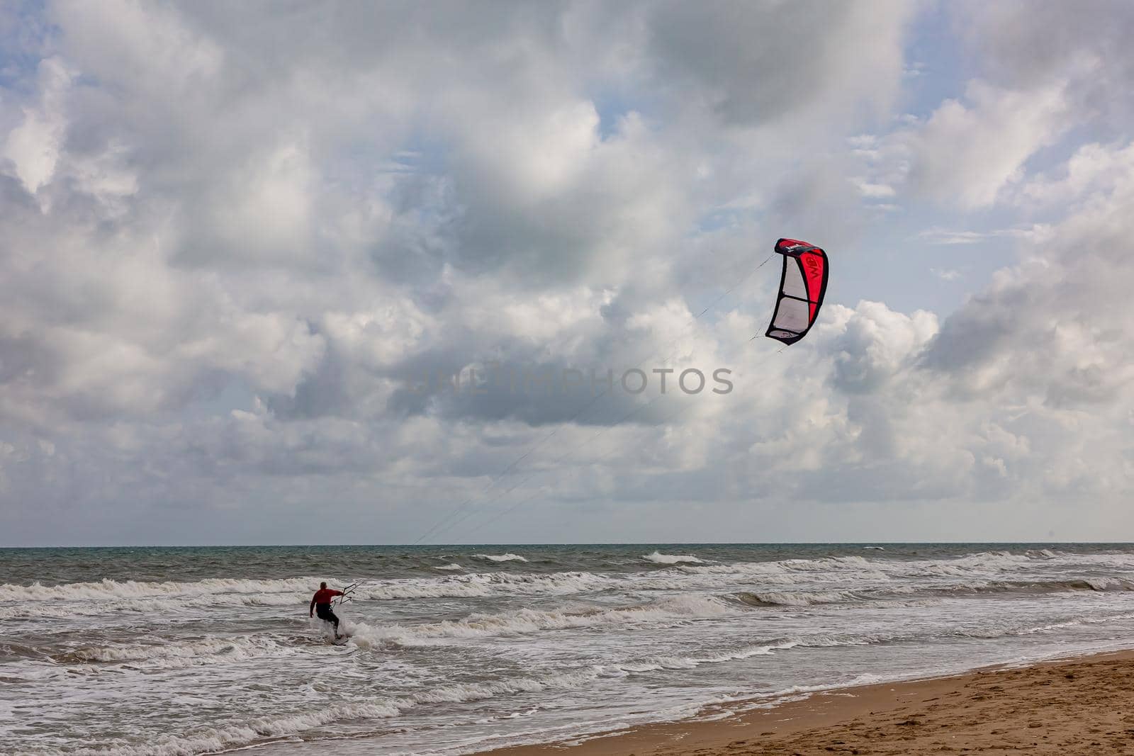 Professional kiter makes the difficult trick on a beautiful background. Kitesurfing Kiteboarding action photos man among waves quickly goes by Milanchikov