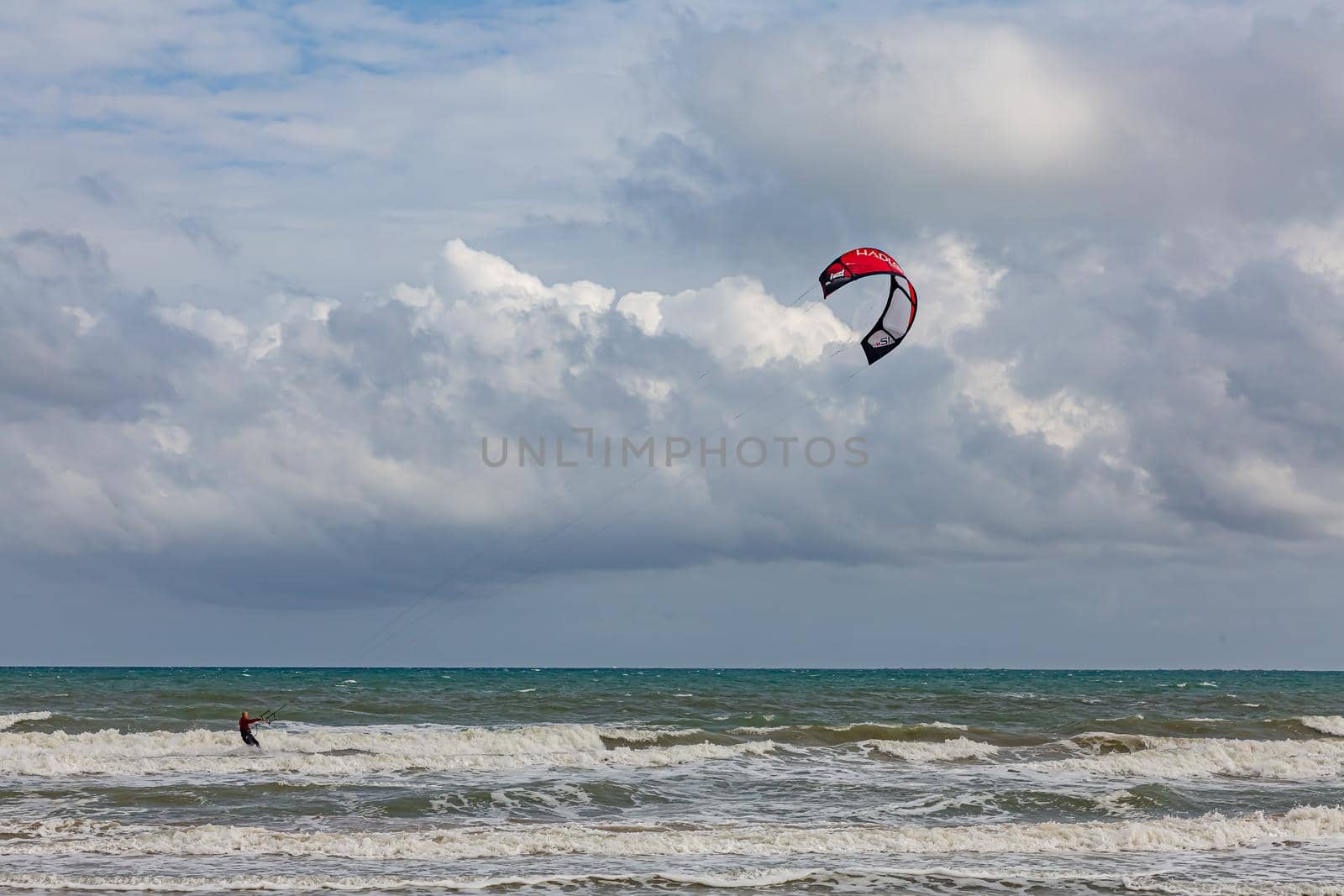 Professional kiter makes the difficult trick on a beautiful background. Kitesurfing Kiteboarding action photos man among waves quickly goes by Milanchikov