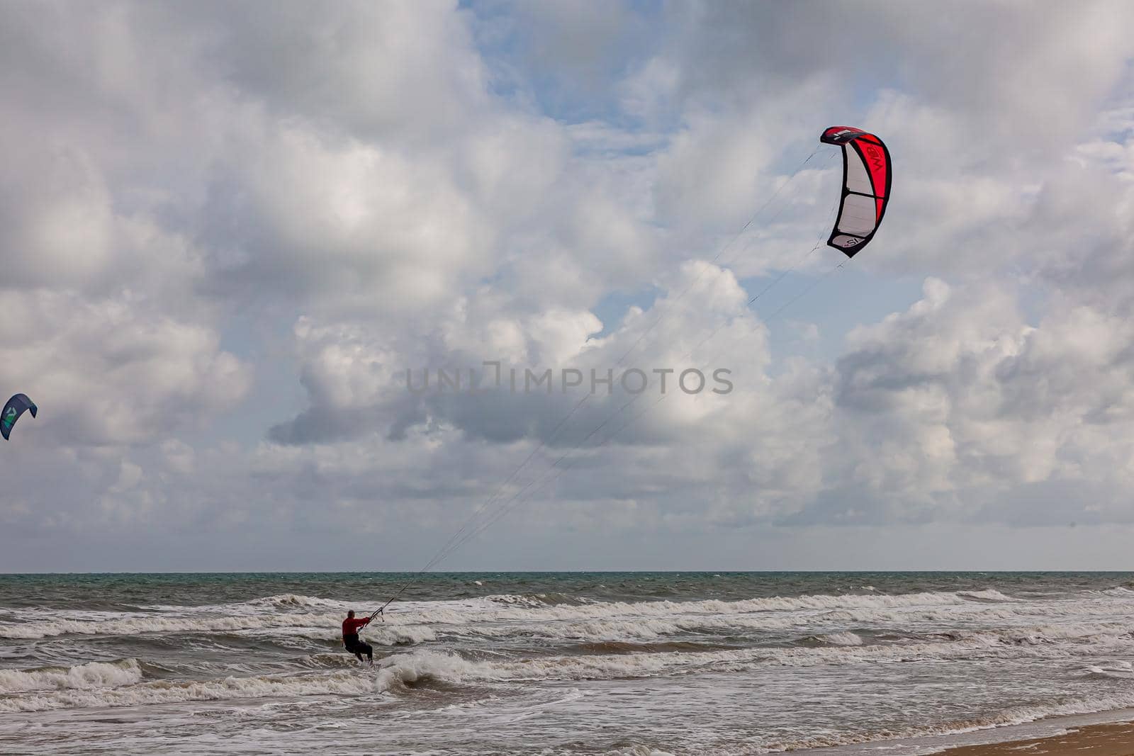 Professional kiter makes the difficult trick on a beautiful background. Kitesurfing Kiteboarding action photos man among waves quickly goes.