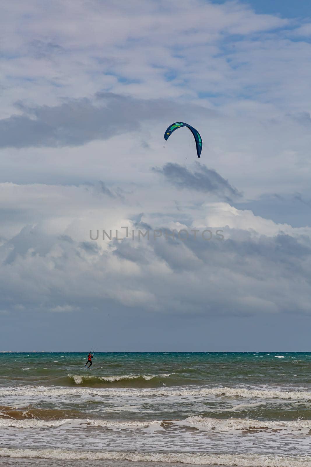 Professional kiter makes the difficult trick on a beautiful background. Kitesurfing Kiteboarding action photos man among waves quickly goes by Milanchikov