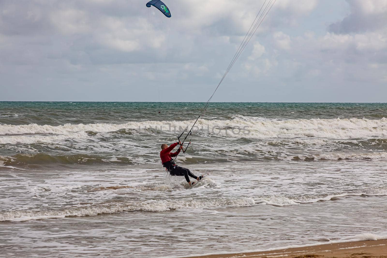 Professional kiter makes the difficult trick on a beautiful background. Kitesurfing Kiteboarding action photos man among waves quickly goes.