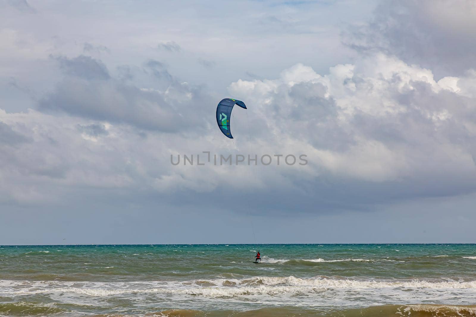 Professional kiter makes the difficult trick on a beautiful background. Kitesurfing Kiteboarding action photos man among waves quickly goes by Milanchikov