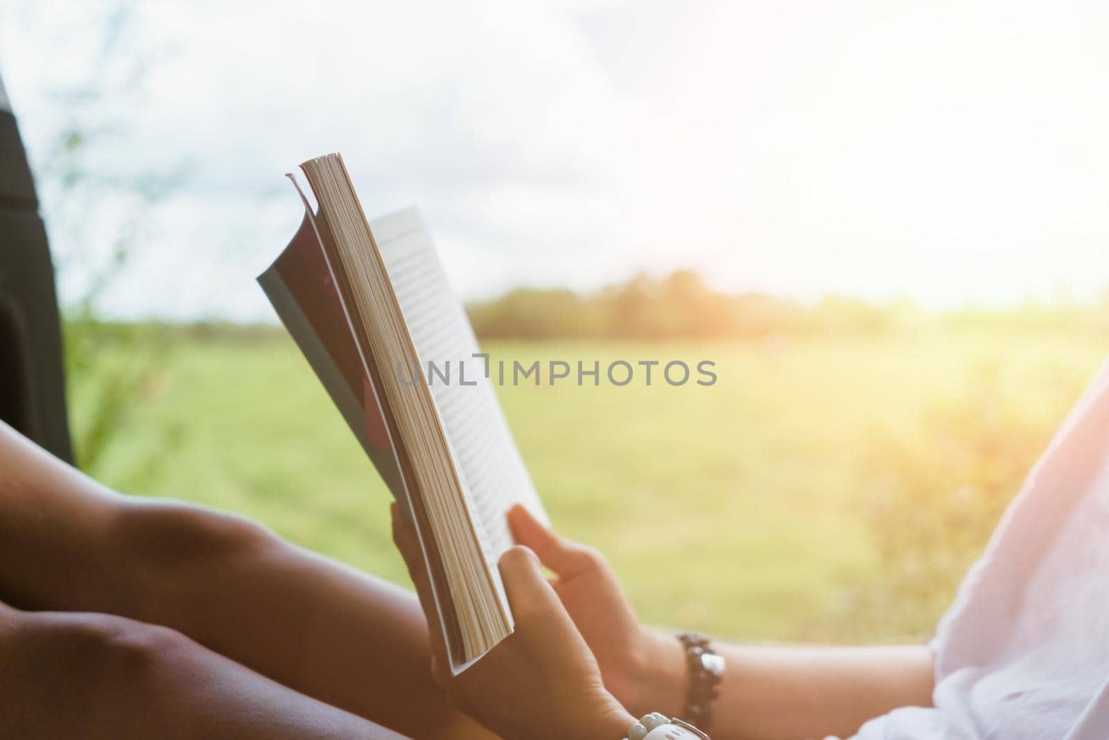 Woman is reading book in beautiful park and pond relax and peaceful environment background.