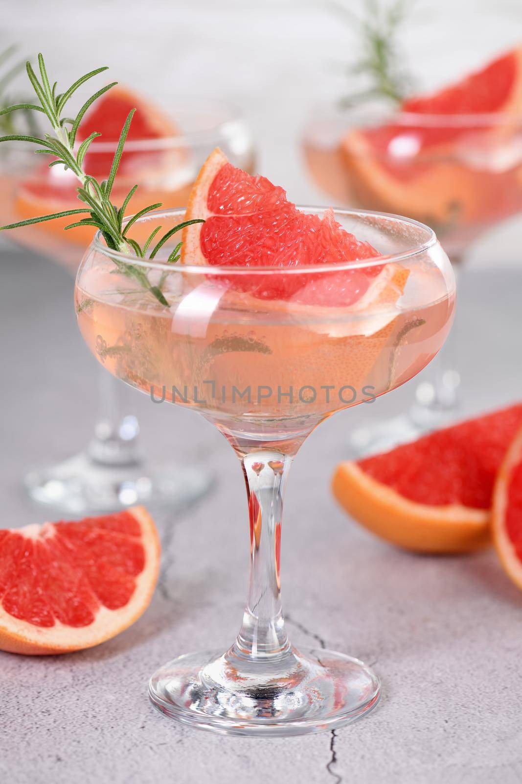 Goblet of sparkling wine with a slice of grapefruit and a sprig of rosemary