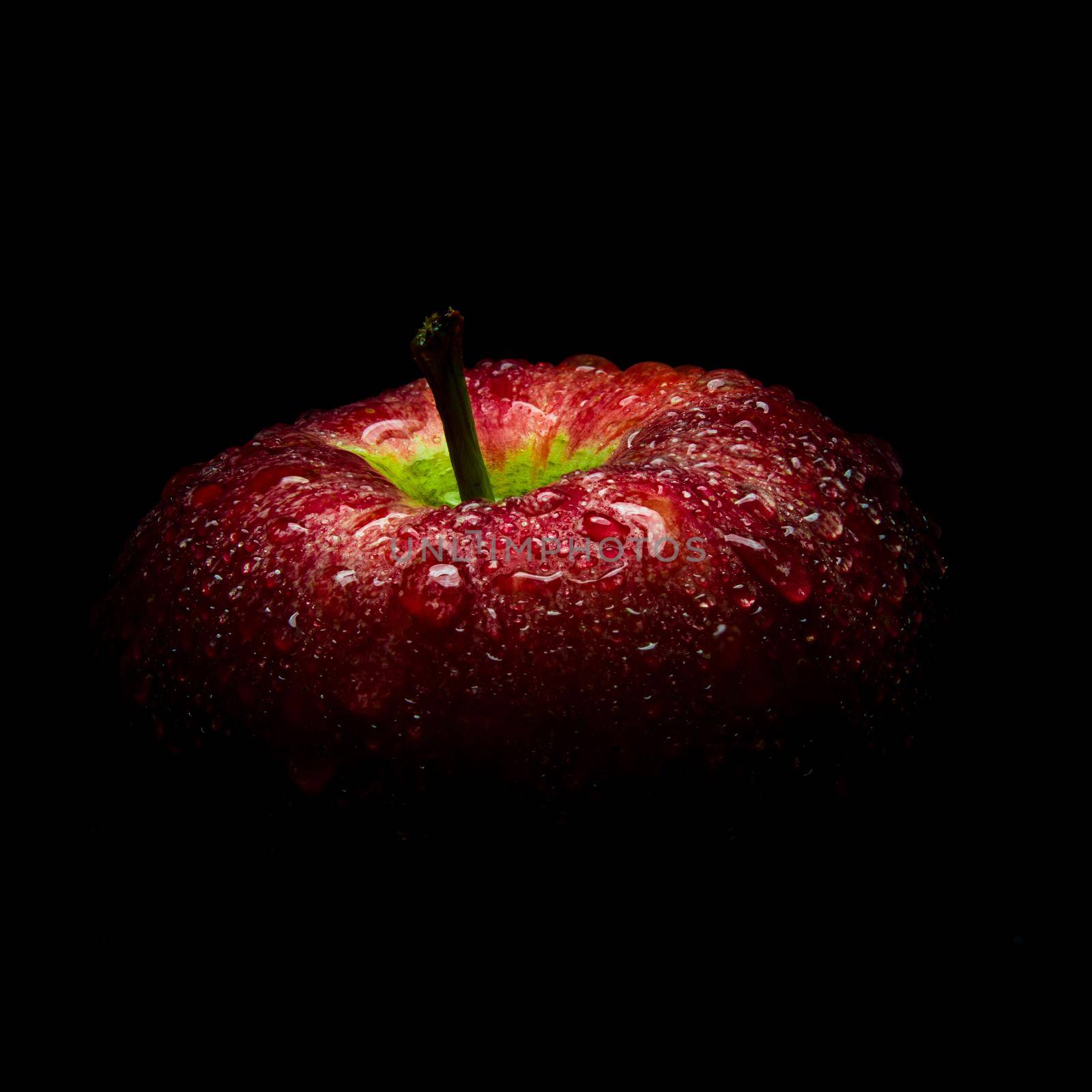 Water droplet on glossy surface of red apple on black background by Satakorn