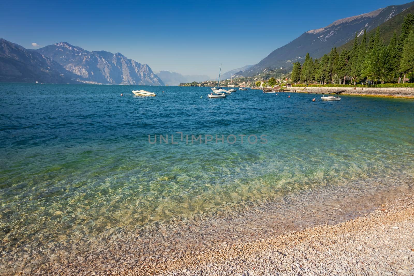 Idyllic lake Garda coastline in Malcesine with sailboats and mountains, Northern Italy