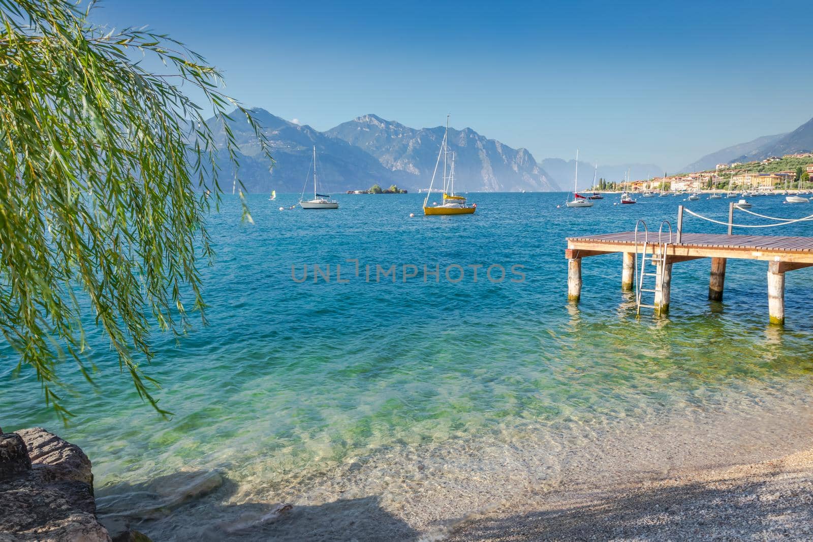 Idyllic lake Garda coastline in Malcesine with sailboats and mountains, Northern Italy