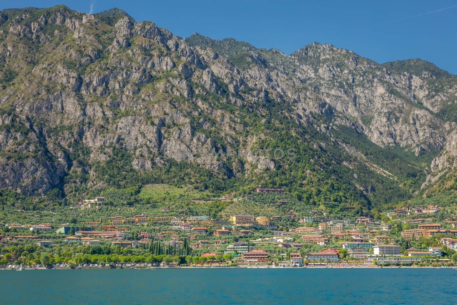 Idyllic Lake Garda and Limone sul Garda old town with motorboat, Italian alps
