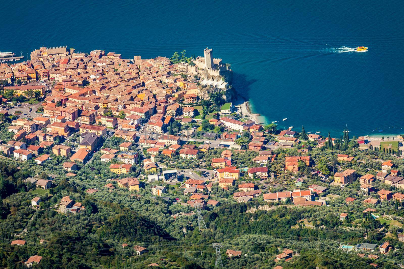 Idyllic Lake Garda above Malcesine old town with motorboat, Italian alps