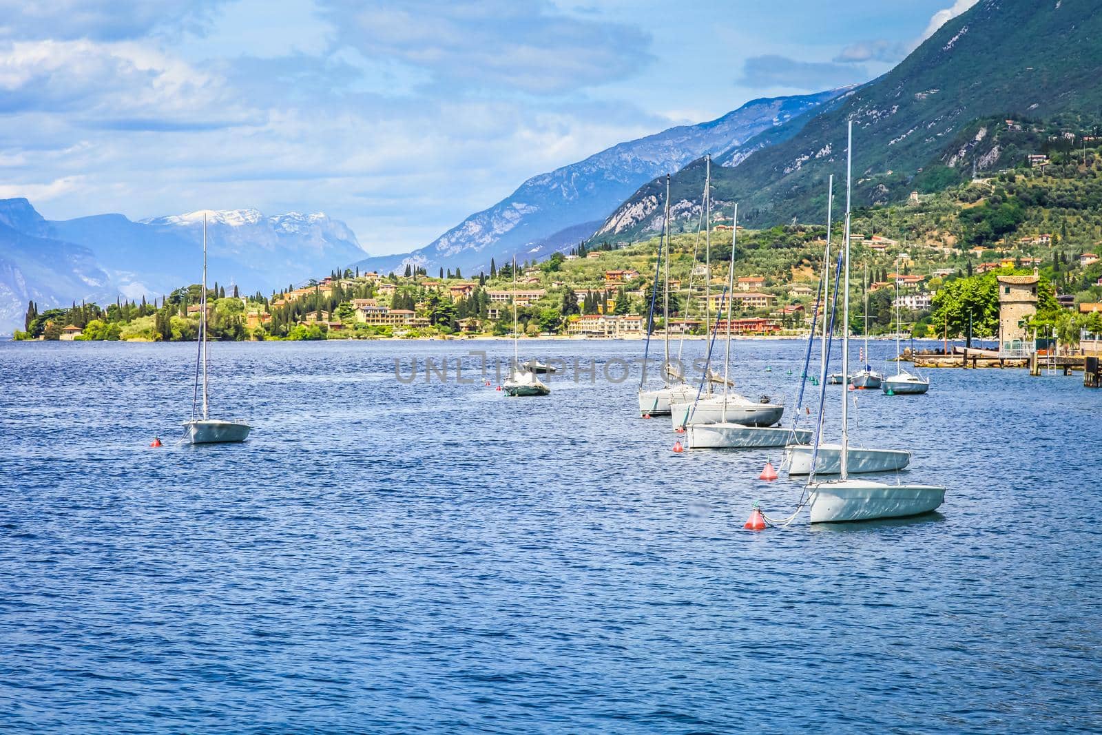Idyllic lake Garda coastline in Malcesine with sailboats and mountains, Northern Italy