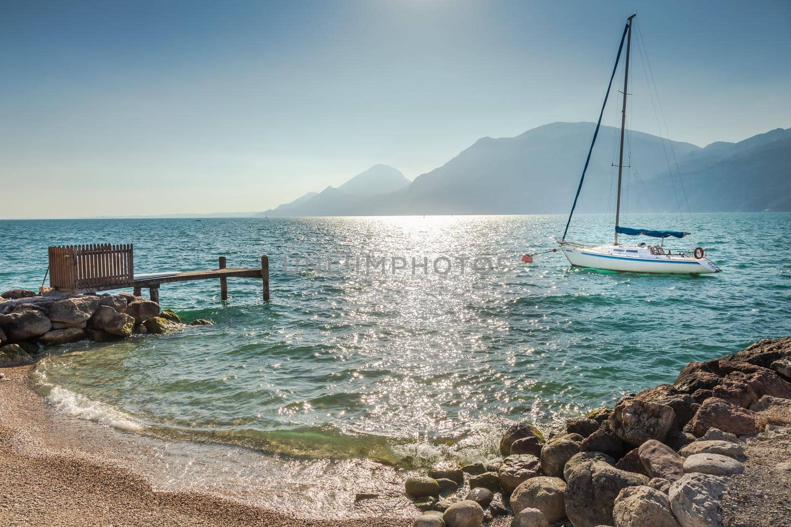 Idyllic lake Garda coastline in Malcesine with sailboats and mountains, Northern Italy