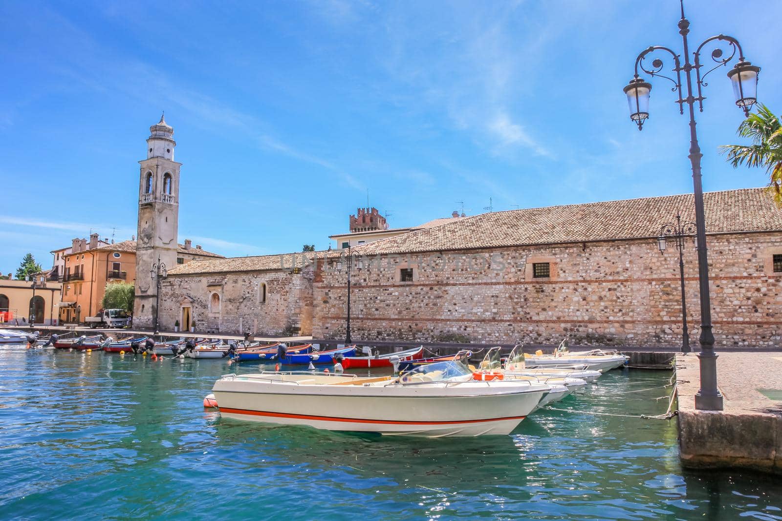 Idyllic lake Garda coastline in Lazise with boat and mountains, Northern Italy