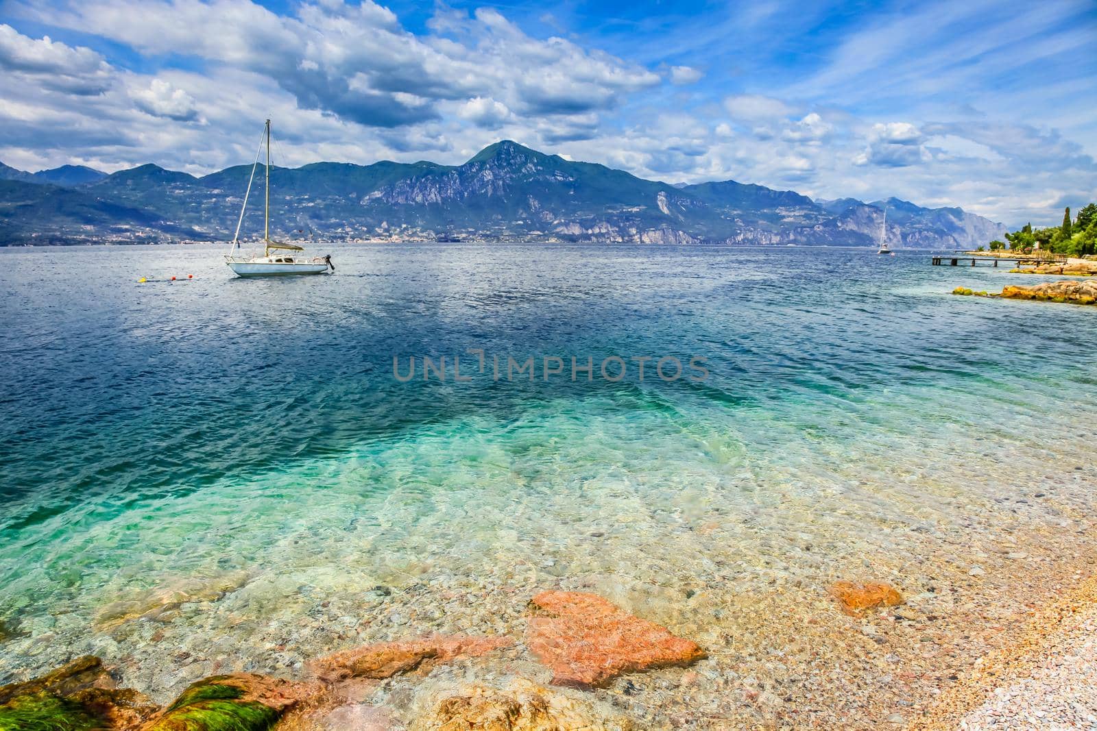 Idyllic lake Garda coastline in Malcesine with sailboats and mountains, Northern Italy