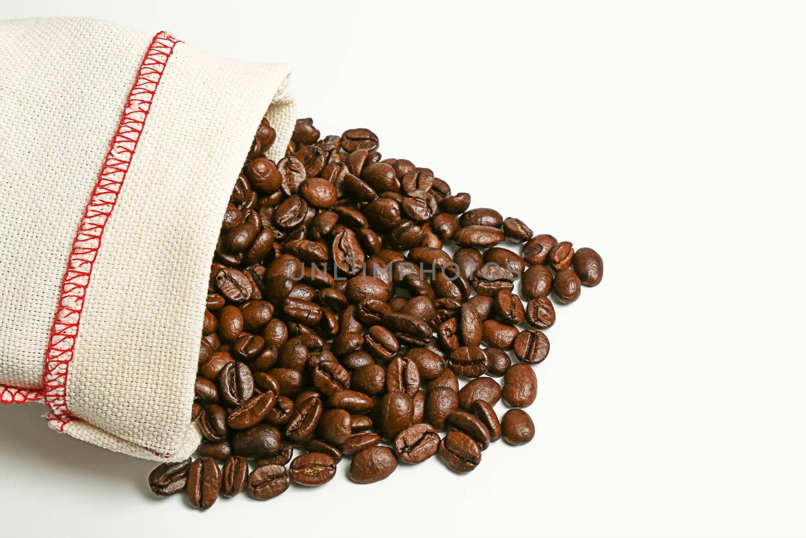 Coffee beans spilled out of the bag on a white background. Isolate. Roasted coffee seeds.