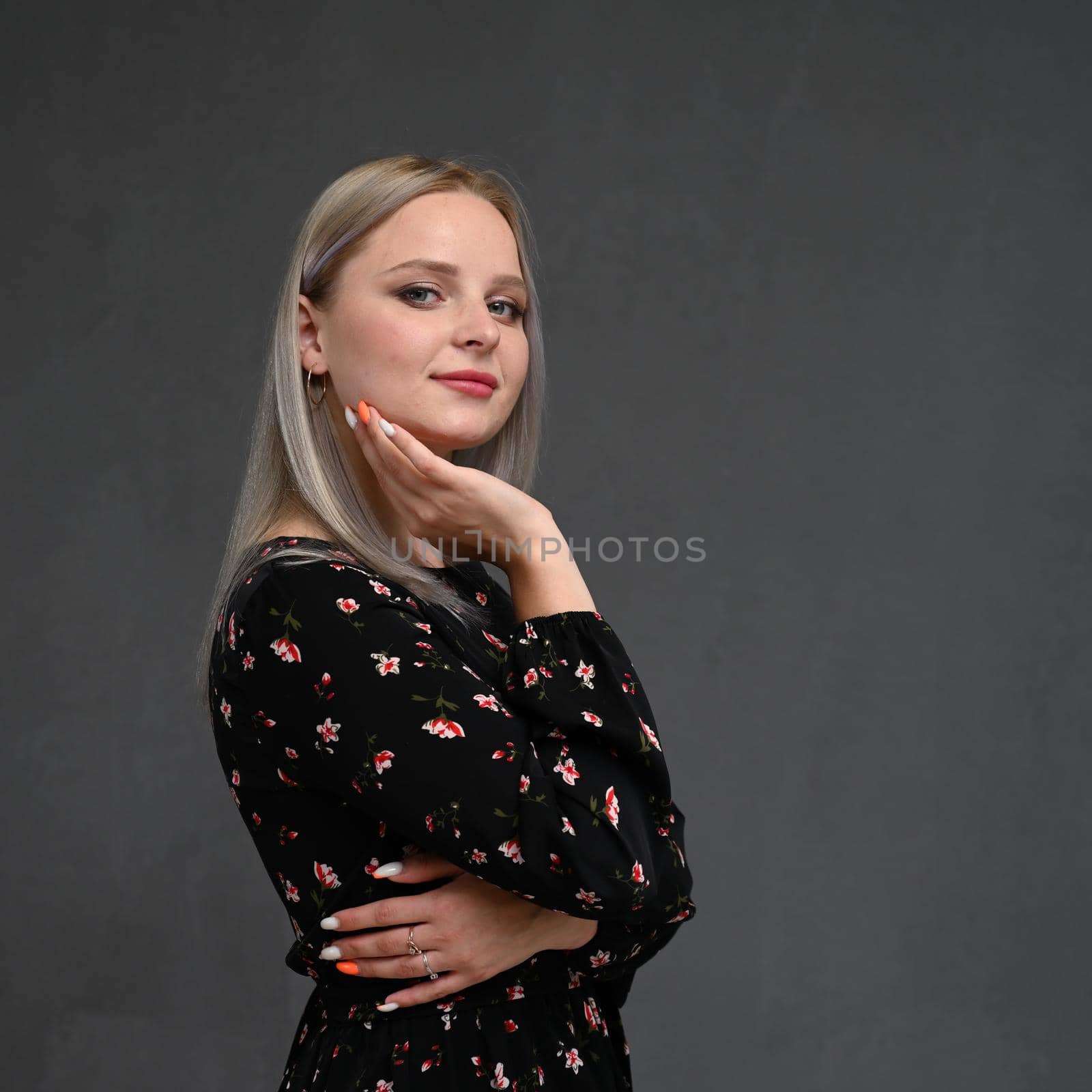 Portrait of a cheerful blondy girl on a gray background.