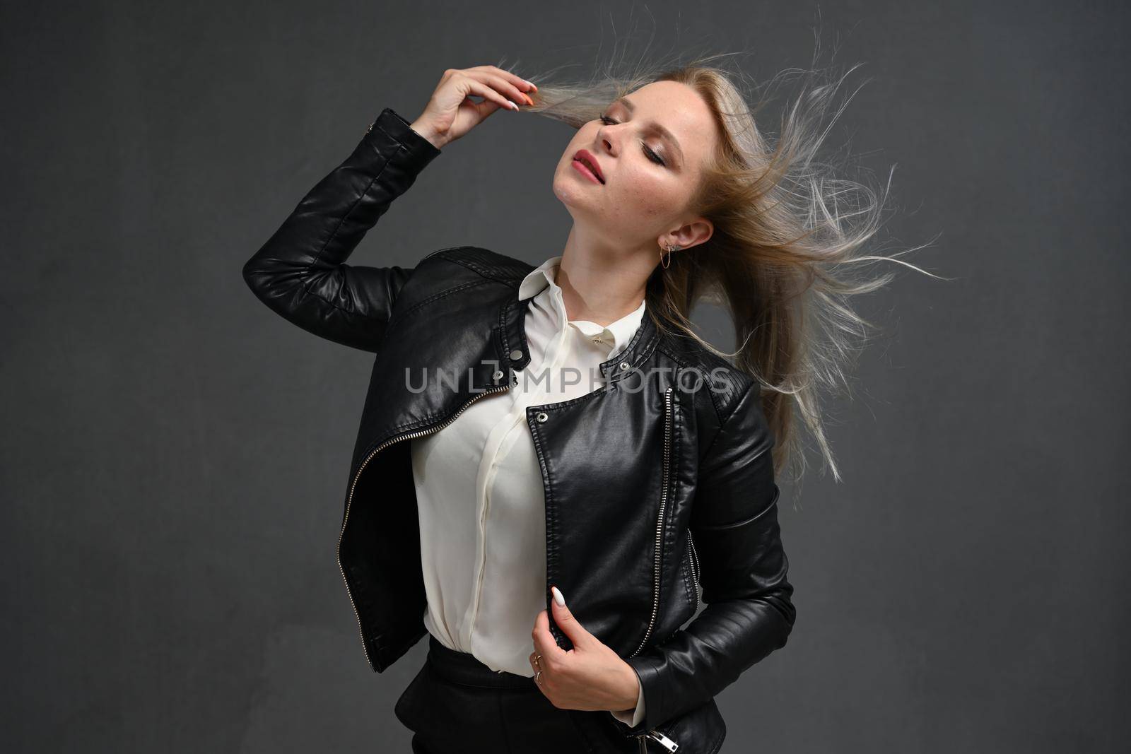 Portrait of a beautiful woman with a long blond hair. Young model with beautiful hair - isolated on gray background. Young girl with hair flying in the wind. by chichaevstudio