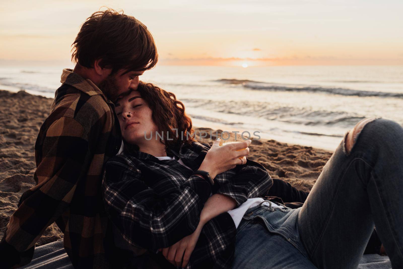 Woman leans in her boyfriend, young couple meets dawn on the seashore together by Romvy