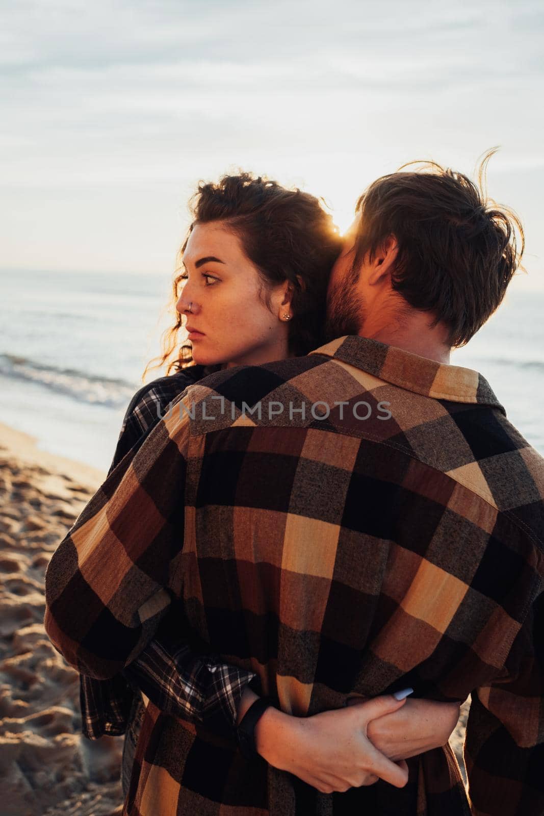 Young woman and man hugging on the background of sea and sunlight