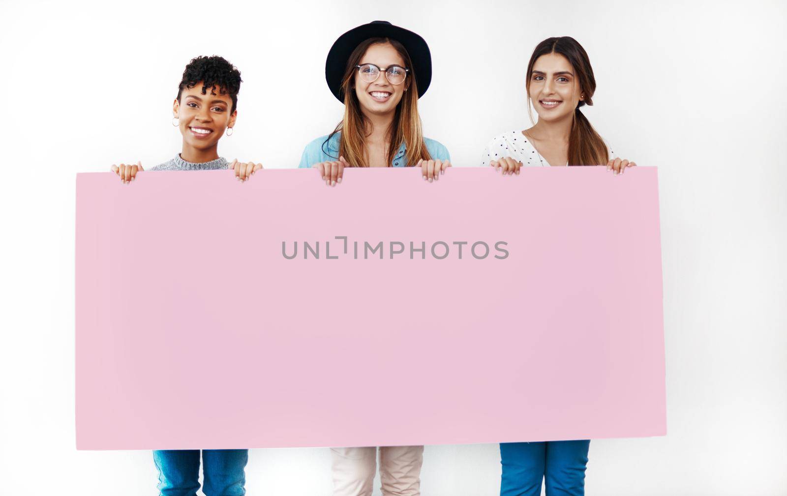 Now thats some trendy looking copy space. Studio shot of a group of young women holding a blank placard against a white background. by YuriArcurs