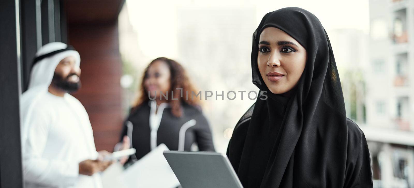 This is how she does business. an attractive young businesswoman dressed in Islamic traditional clothing using a tablet on her office balcony