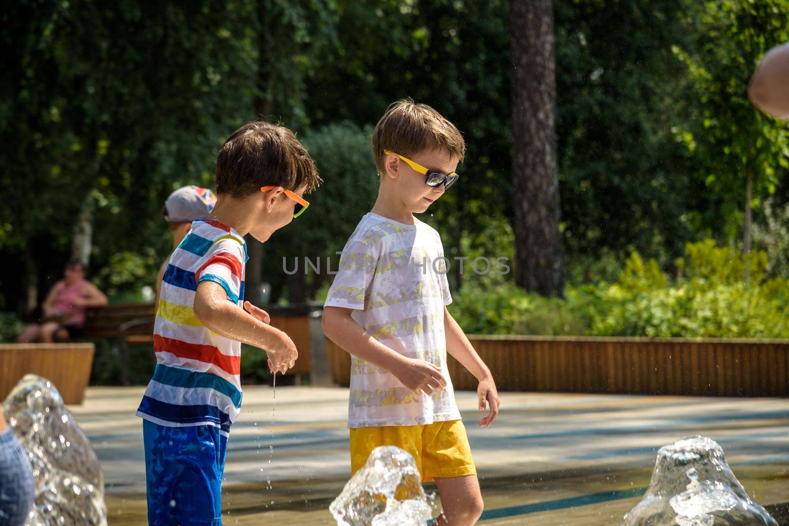 Boy having fun in water fountains. Child playing with a city fountain on hot summer day. Happy kids having fun in fountain. Summer weather. Active leisure, lifestyle and vacation.