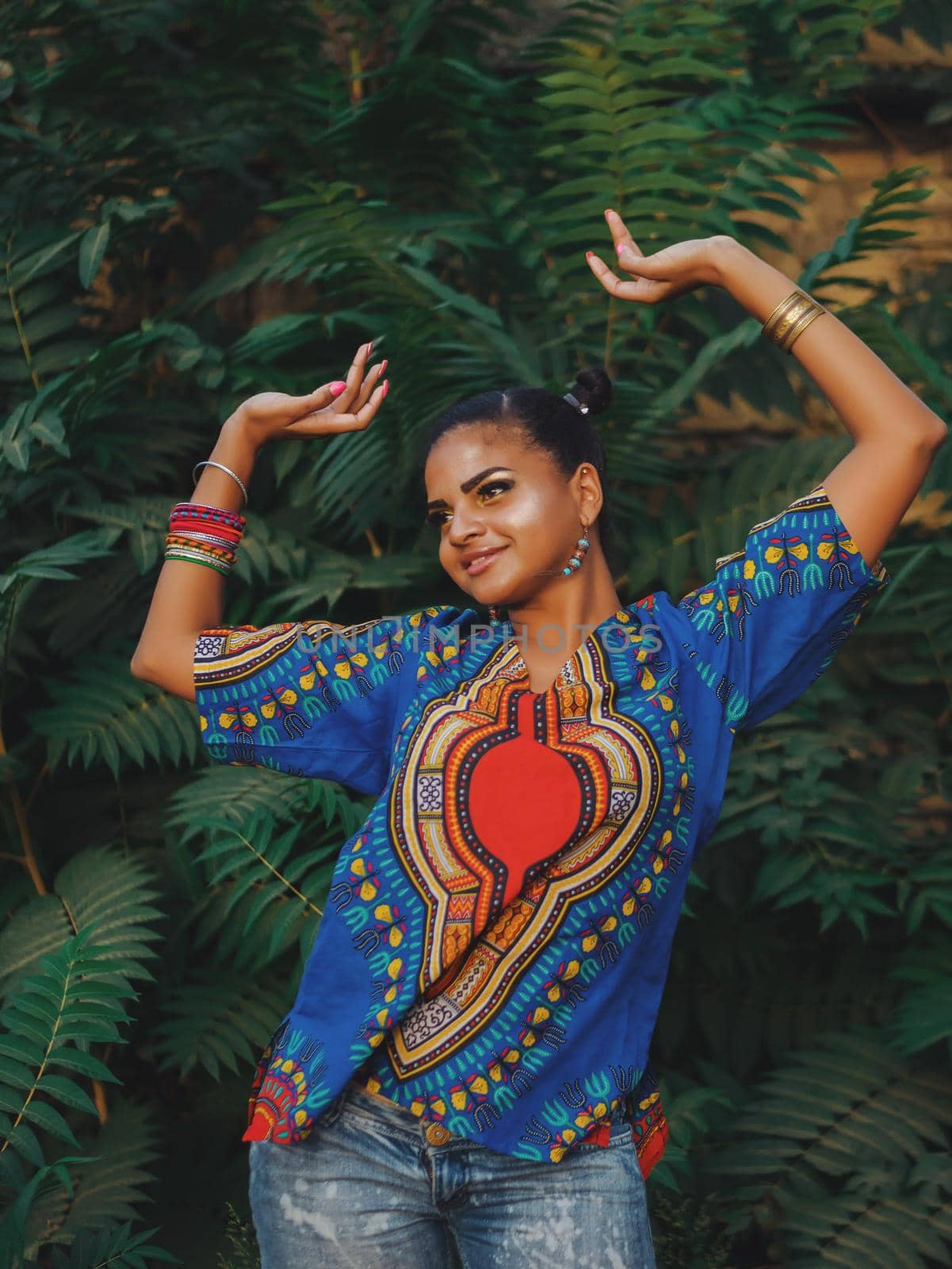 Afro-american woman outdoor. Multi ethnic girl wearing colorful clothing posing, enjoys the nature. Green tropical background