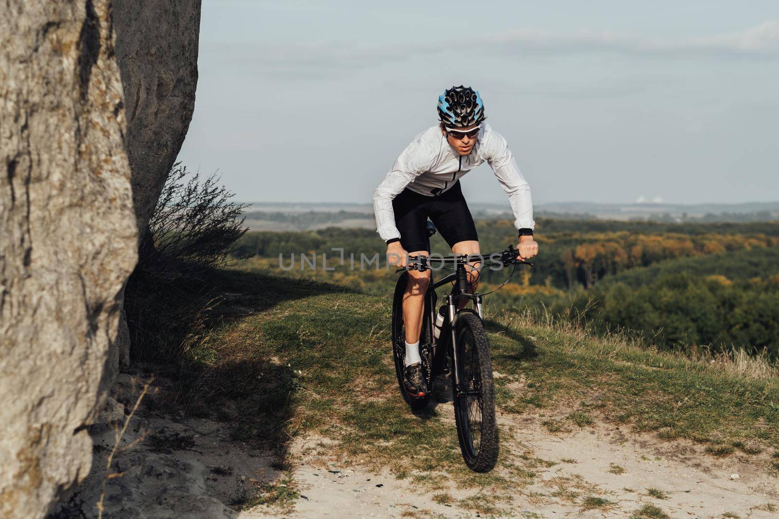 Equipped Professional Male Cyclist Riding Bike Outdoors on Top of Hill