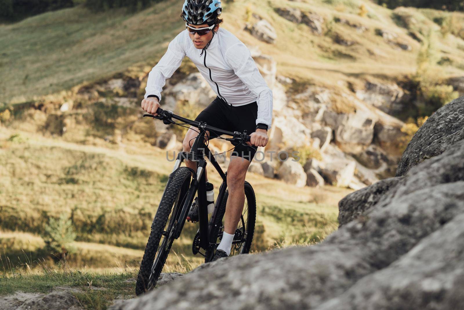 Close Up Professional Male Cyclist Riding Mountain Bike on Trail Among Rocky Terrain