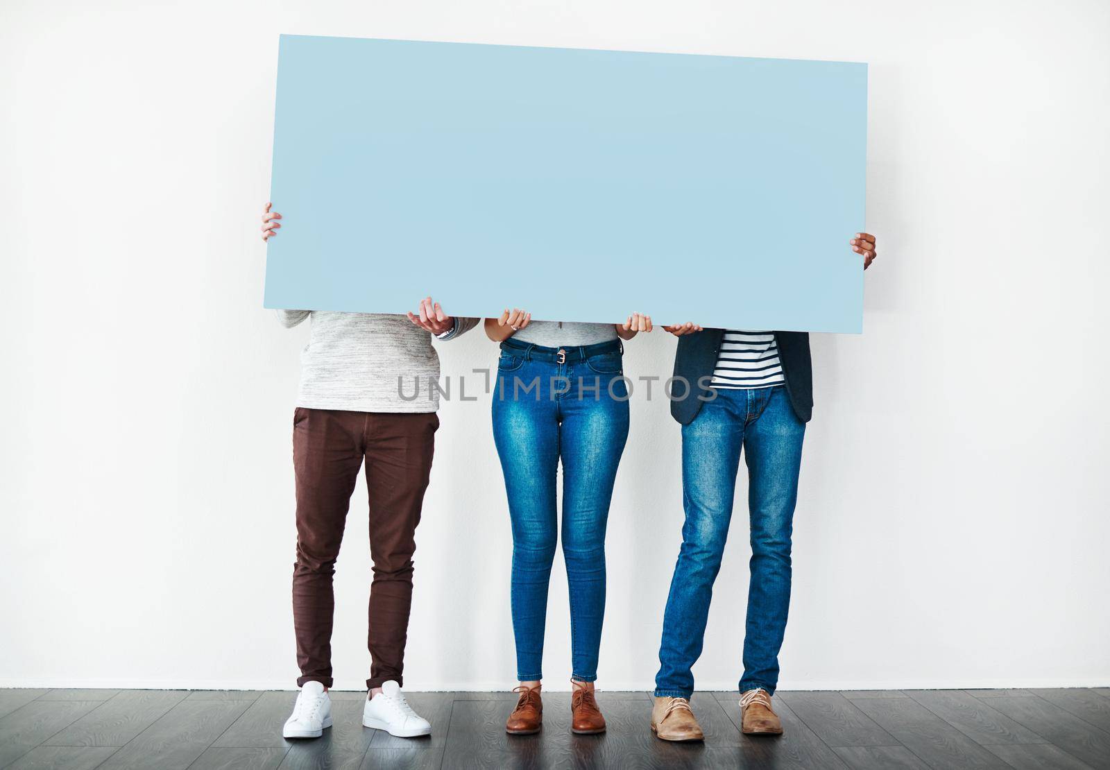 Say whats on your mind. Studio shot of a group of people covering themselves with a blank placard against a white background