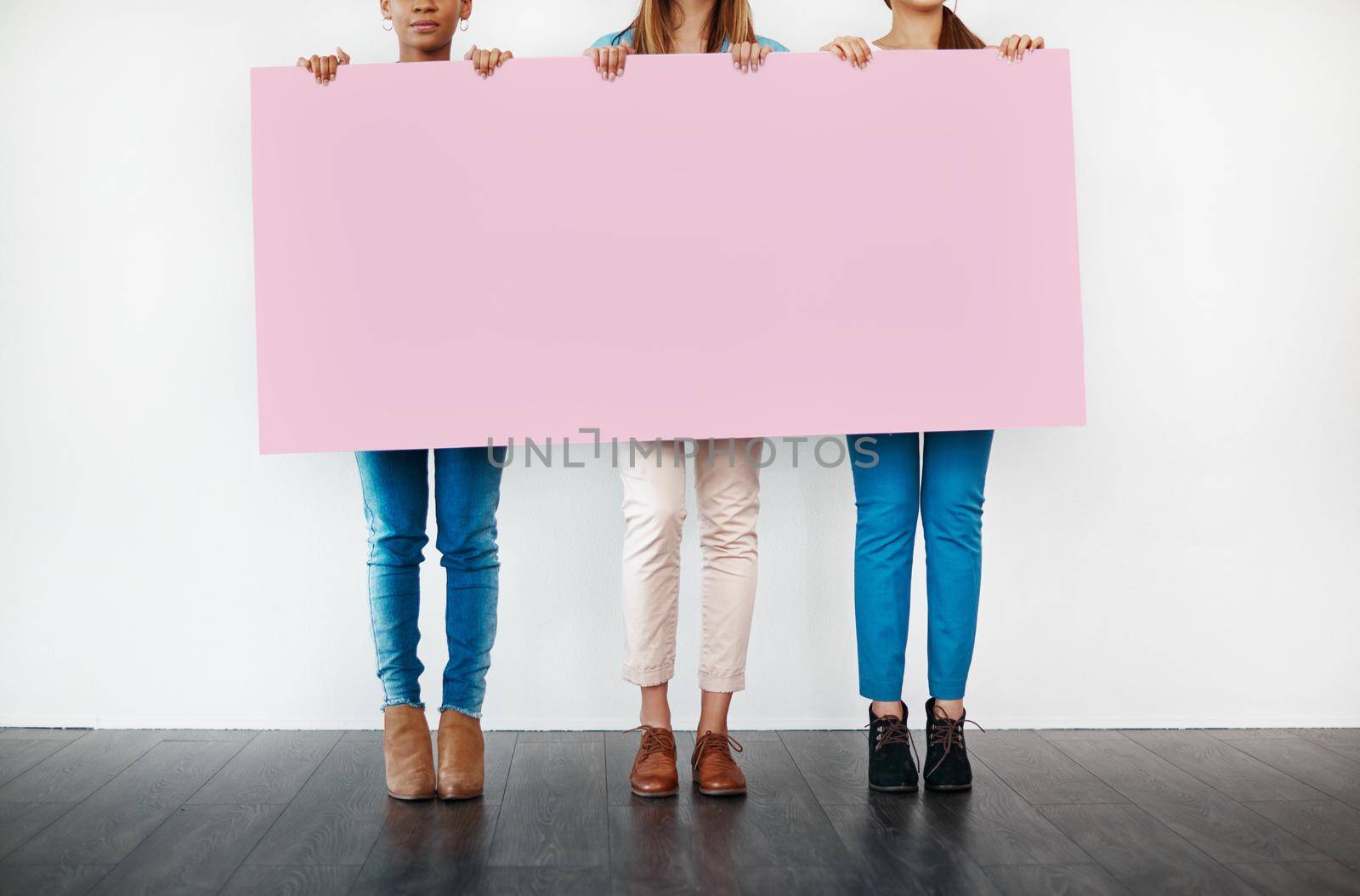 Something for the ladies... Cropped studio shot of a group of young women holding a blank placard against a white background. by YuriArcurs