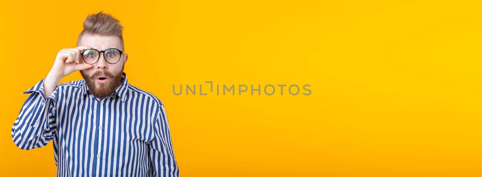 Young man with a mustache and beard making bulging eyes in surprise against a white background. Concept of surprise and uncertainty