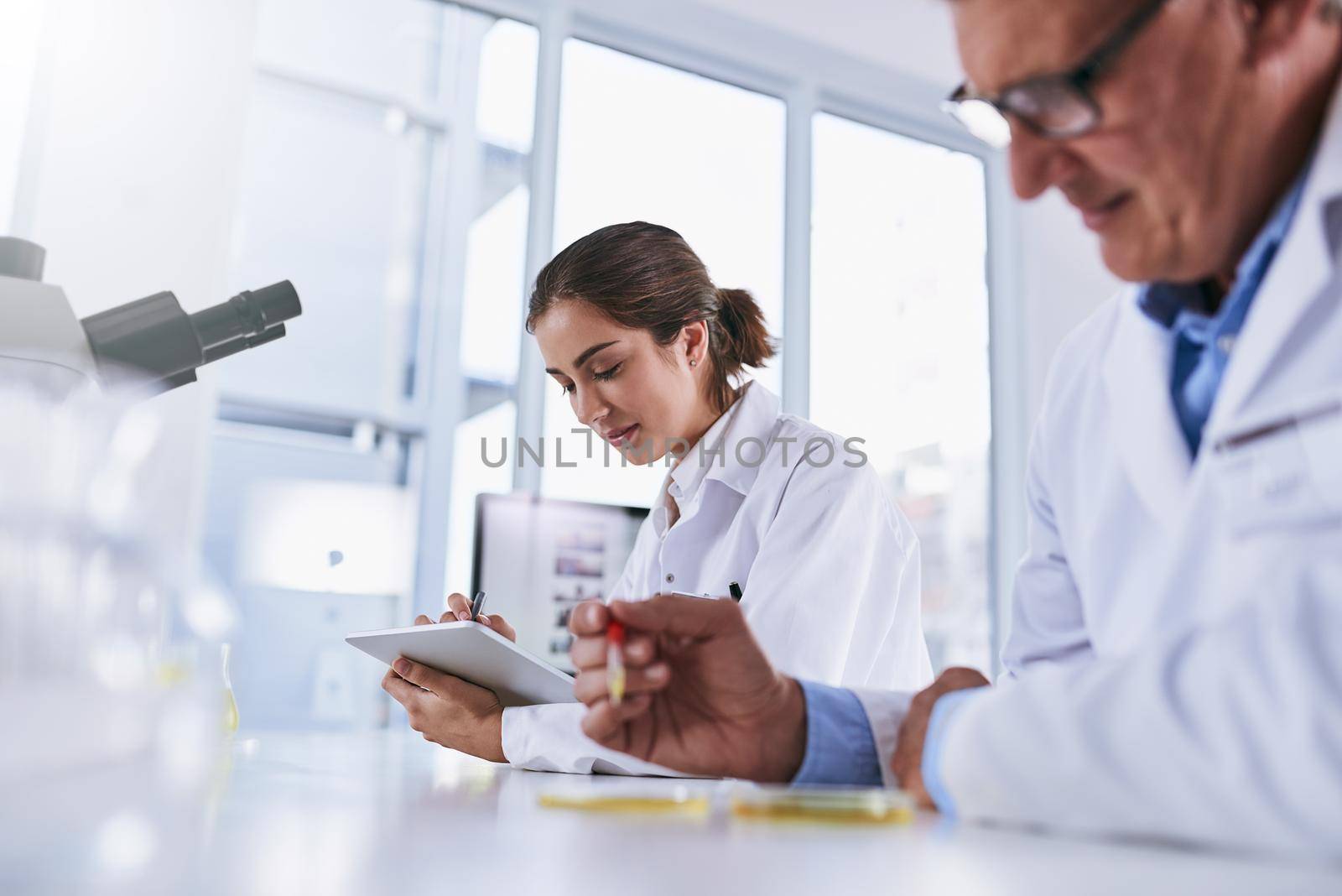 Advanced technology to help advance the sciences. two scientists working in a lab. by YuriArcurs