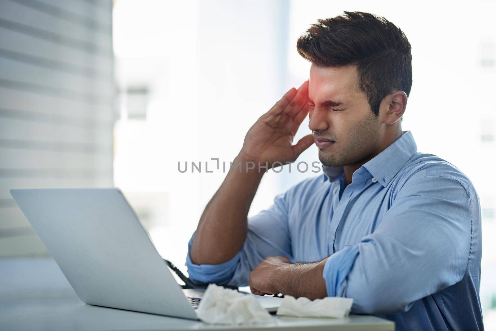 Its hard to have a productive day when headaches strike. a young businessman suffering with a headache at work. by YuriArcurs