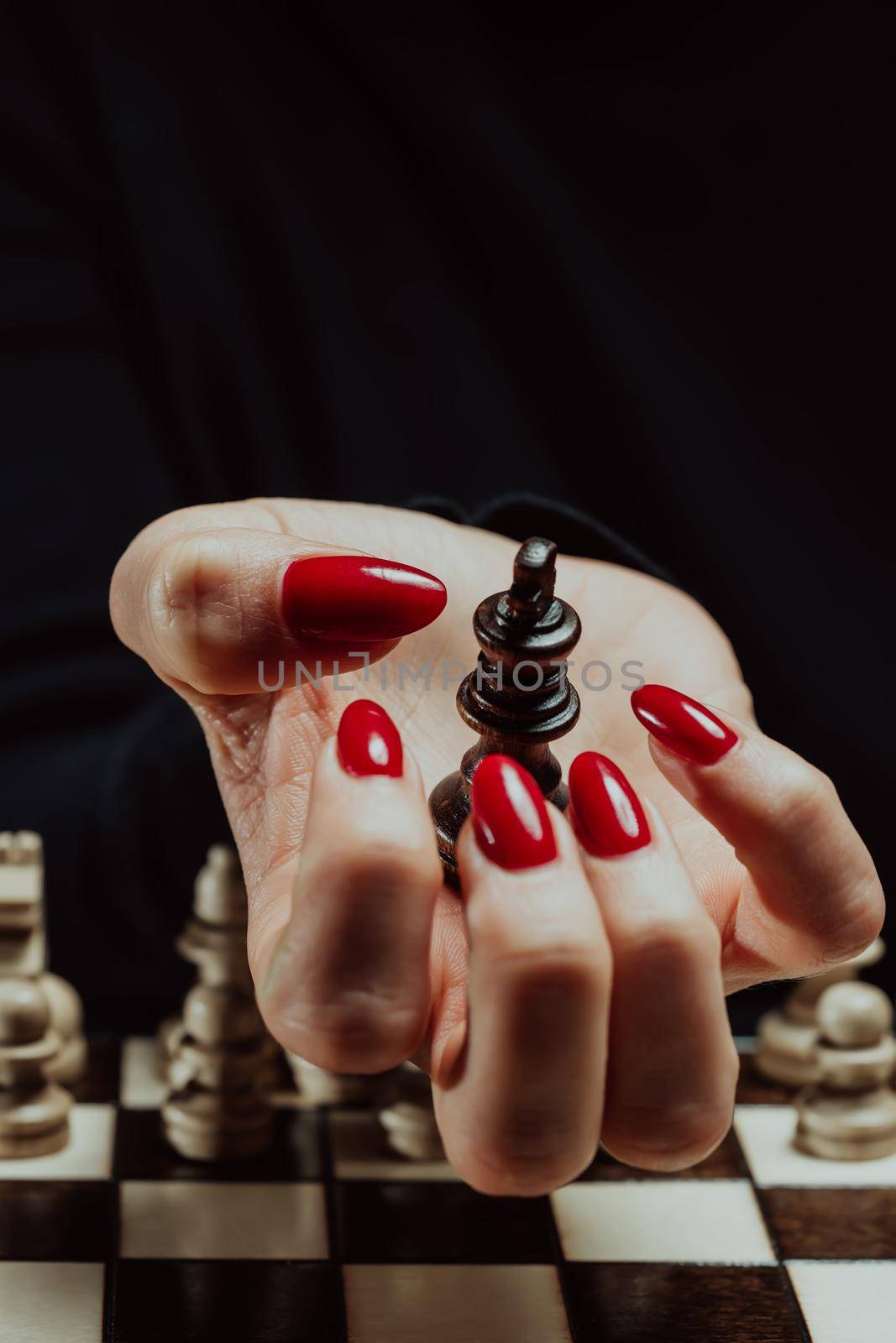 Woman holds in her hand the opponent's chess king in board intelligence game. Lady wins round. Victory over enemy, power concept. Board strategy, success business, old vintage pieces. High quality